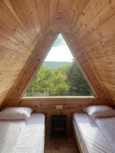 two beds in a room with a large window at Komovi - Kobil Do Guesthouse in Kolašin +128 photos