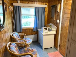 a bathroom with two chairs and a sink and a window at Mummon mökki - Granny´s cottage in Suonenjoki