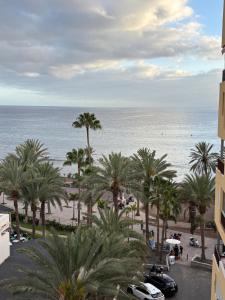 - une vue sur la plage et les palmiers depuis un bâtiment dans l'établissement Apartamento con Vistas al Mar, à Los Cristianos