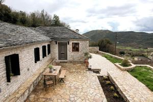 a stone house with a patio and a table and chairs at Alexandros private house in Ano Pedina