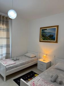 a bedroom with two beds and a lamp and a picture at Marinela Apartment 2 in Tirana