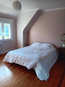 ein Schlafzimmer mit einem Bett mit einer weißen Tagesdecke in der Unterkunft Maison de vacances in Lannion