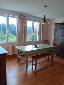 ein Esszimmer mit einem grünen Tisch und Fenstern in der Unterkunft Maison de vacances in Lannion