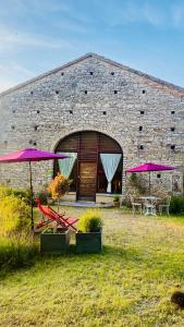 a brick building with tables and chairs and umbrellas at La bastide de Meilhouret in Larroque