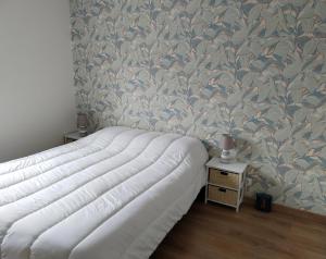 a bedroom with a large bed with a wall at Charmante maison neuve au cœur de Matignon in Matignon