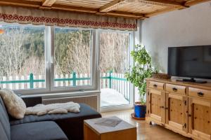 ラムサウ・アム・ダッハシュタインにあるLandhaus & Ferienwohnungen Bergrastのソファと大きな窓のあるリビングルーム