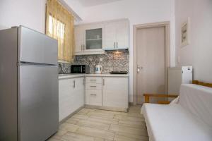 a kitchen with white cabinets and a refrigerator at Studio Evaggelia Sea View in Skala Marion +7 photos