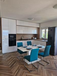 a kitchen with a table and blue chairs in a kitchen at Apartment MILA in Senj