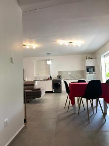 a kitchen and living room with a red table and chairs at jadelys loc in Sainte-Anne