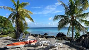 a boat and chairs on a beach with palm trees at Fareana Lodge Bungalow ho'e in Fakarava