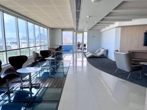 an office lobby with chairs and tables and windows at Suíte com jardim e piscina na Barra Olímpica RJ in Rio de Janeiro