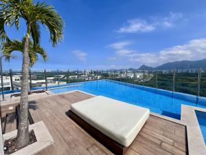 a swimming pool with a bed on a balcony with a palm tree at Suíte com jardim e piscina na Barra Olímpica RJ in Rio de Janeiro