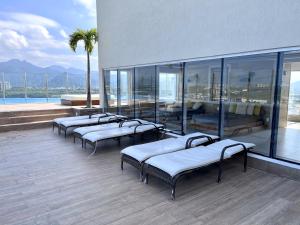 a row of beds in a building with windows at Suíte com jardim e piscina na Barra Olímpica RJ in Rio de Janeiro
