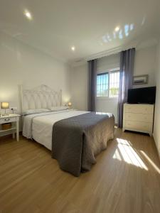 a bedroom with a large bed and a television at Sunset Palm in El Puerto de Santa María