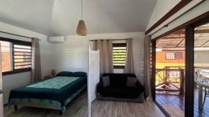 a bedroom with a bed and a chair in it at Fareana Lodge Bungalow ho'e in Fakarava