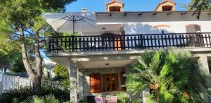 a white house with a balcony with an umbrella at Patrizia's Maison in Ripatransone