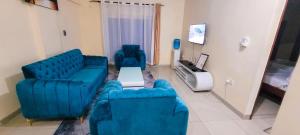 ein Wohnzimmer mit 2 blauen Sofas und einem TV in der Unterkunft Palm Terraces in Mombasa
