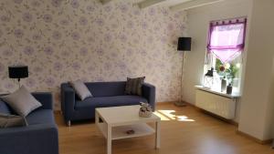 ein Wohnzimmer mit einem blauen Sofa und einem Tisch in der Unterkunft Ferienhaus Rheiderland in Ditzumerverlaat