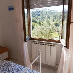 a bedroom with a large window and a bed and radiator at La Collina in Riccò del Golfo di Spezia