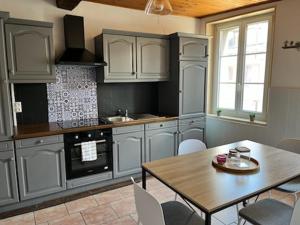 a kitchen with white cabinets and a table and a dining room at L escale in Givet