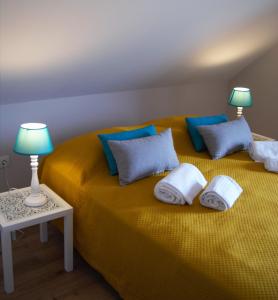 een geel bed met blauwe kussens en 2 lampen erop bij O Forte Guest House in Peniche