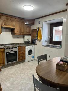 a kitchen with a table and a stove and a microwave at Casa Familiar con barbacoa in Finisterre