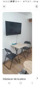 a table with two chairs and a tv on a wall at Echarvines in Talloires