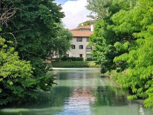 a river with a building in the background with trees at Luxury Room & Private Spa - Rio Botteniga in Treviso