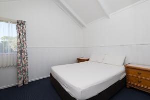 a bedroom with a bed and a window at Waitangi Holiday Park in Paihia