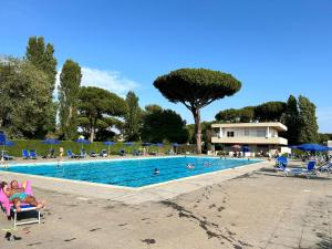 una piscina con gente sentada en sillas en el agua en Spaziosa Villa con piscina, BBQ e campi da tennis, en Casal Palocco