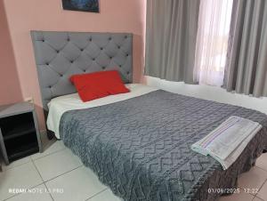 a bedroom with a bed with a red pillow on it at departamento familiar, Tarija te espera!! in Tarija