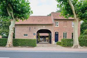 a red brick building with an archway and trees at Hof ter Wallen in Zoutleeuw