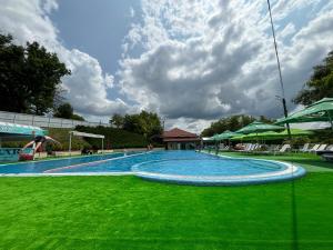 a large swimming pool with green grass and clouds at Raiax in Hînceşti