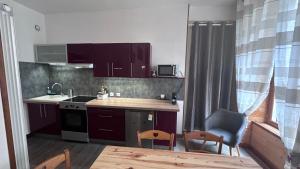 Una cocina con gabinetes morados y una mesa y sillas. en Appartement 4 à 6 personnes Hyper Centre au Calme dans impasse AVEC PARKING, en Cauterets
