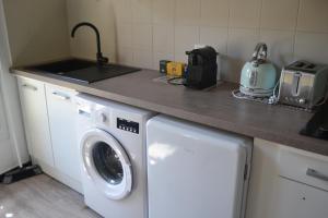 a kitchen with a washing machine and a counter at Appartement Proche Quai Rouget in LʼIsle-sur-la-Sorgue +4 photos