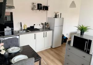 eine Küche mit weißen Schränken und einem weißen Kühlschrank in der Unterkunft Le Ptit Maisy in Grandcamp-Maisy