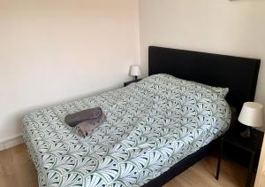 ein Bett mit einer schwarzen und weißen Bettdecke und einem Kissen in der Unterkunft Le Ptit Maisy in Grandcamp-Maisy