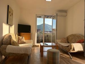 sala de estar con 2 sillas, mesa y ventana en Green square apartment Budva, en Budva