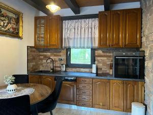 a kitchen with wooden cabinets and a table and a window at Kuća za odmor LO in Lipovlje