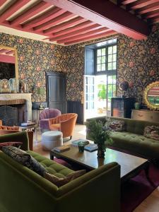 a living room with green furniture and a fireplace at Chambres d'hôtes La Massonnière avec grand jardin - idéal familles, groupes et séjour nature - Sarthe in Saint-Christophe-en-Champagne