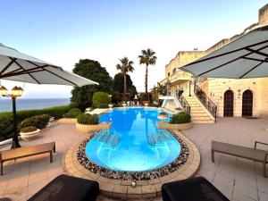 a swimming pool with chairs and an umbrella at Madliena Hills Mansion in Is-Swieqi
