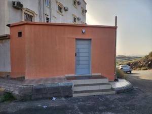 a small orange building with a blue door on it at استوديو للايجار in Quai