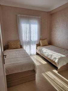 a bedroom with two beds and a window at Appartement Sofia in Martil