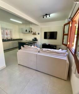 un salon avec trois canapés blancs devant une cuisine dans l'établissement Casa Climatizada-2km centro Histórico, à Parati