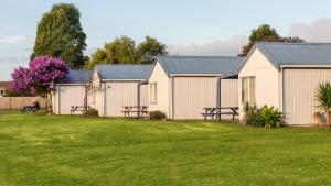 eine Reihe weißer Gebäude mit einem Rasenplatz in der Unterkunft Waitangi Holiday Park in Paihia