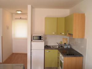cocina con armarios verdes y nevera blanca en Apartments Vala, en Rogoznica