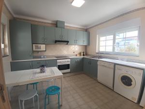 a kitchen with blue cabinets and a table and stools at Apartamento em D'el Rey-Obidos Beach & Surf in Amoreira