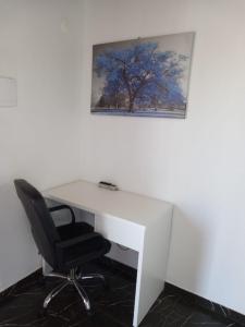 a white desk with a chair and a picture on the wall at Loft em São José in São José