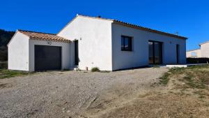 un bâtiment blanc avec un garage sur un chemin de terre dans l'établissement Cap sur le Ventoux, à Mormoiron
