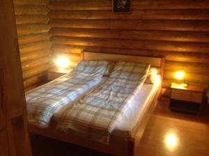 a bed in a wooden room with two lamps at Relax Apartman in Hajdúszoboszló